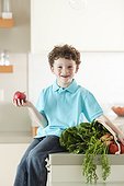 USA, Utah, Portrait of smiling boy (6-7) holding apple and vegetables in kitchen
