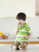 USA, Utah, Boy (4-5) eating kiwi in kitchen
