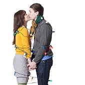 Studio shot of young couple kissing wrapped in illuminated Christmas lights