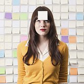Studio shot of young woman looking at post-it note on forehead