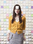 Studio shot of young woman looking at post-it note on forehead