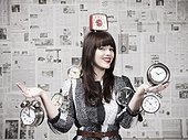 Studio shot of young woman holding alarm clocks
