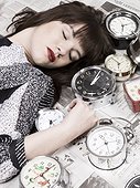 Studio shot of sleeping woman and alarm clocks