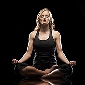 Studio shot of young woman meditating in lotus position