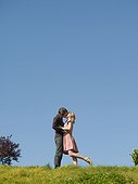 Couple kissing on hill against clear sky