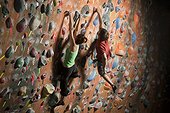 Young woman and mid adult man climbing on wall