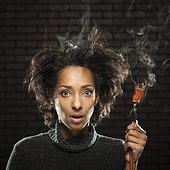 Studio shot of woman holding smoking electric plug