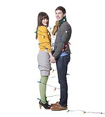 Studio shot of young couple wrapped in Christmas lights