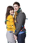 Studio shot of young couple wrapped in Christmas lights