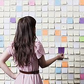 Studio shot of young woman in front of wall covered in adhesive notes