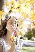 Young woman blowing soap bubbles in Autumn forest
