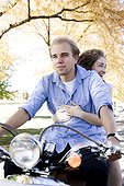 Young couple riding on motorcycle in Autumn forest
