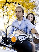 Young couple riding on motorcycle in Autumn forest