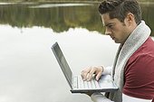 Mature man using a laptop at lakeside