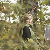 Portrait of a mature woman leaning against a tree and using a laptop