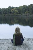 Rear view of a mature woman sitting in lotus position at the lakeside