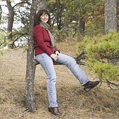 Low angle view of a mature woman sitting on a branch and smiling