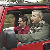 Side profile of two mature men sitting in a jeep
