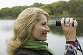 Side profile of a mature woman looking through binoculars and smiling