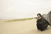 Side profile of a mature woman crouching on the beach