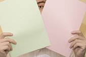 Man peeking through two papers