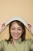 Portrait of a mid adult woman carrying a stack of papers on her head and smiling