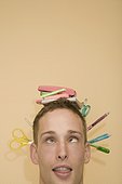 Close-up of a young man with stationery objects on his head
