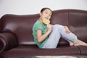 Portrait of a girl sitting on a couch and licking a lollipop
