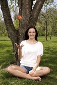 Young woman sitting with an apple on meadow
