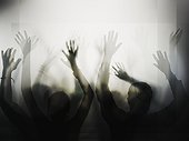 Silhouette of people with raised hands