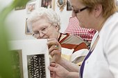 Geriatric nurse and old woman looking into photo album