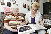 Geriatricnurse and old woman looking into photo album