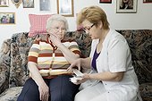 Geriatric nurse explaining medication to old woman