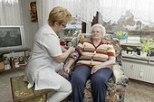 Geriatric nurse taking blood pressure of old woman