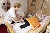 Geriatric nurse bandaging leg of old woman
