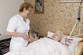 Geriatric nurse talking to old woman in bed