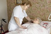 Geriatric nurse talking to old woman in bed