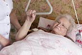 Geriatric nurse and old woman lying in sickbed
