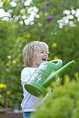 Blond girl with watering can in garden