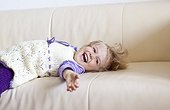 Laughing blond girl lying on couch