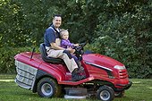 Toddler with father on lawnmower