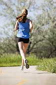 An athletic woman runs along a bike trail on a warm sunny day.
