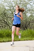An athletic woman runs along a bike trail on a warm sunny day.
