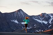 An athletic woman runs along Trail Ridge Road (12,183 feet) near its apex at sunrise, Rocky Mountain National Park, Colorado.