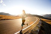 An athletic woman runs along Trail Ridge Road (12,183 feet) near its apex at sunrise, Rocky Mountain National Park, Colorado.