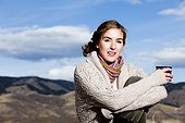 A young woman sips coffee and poses in layered outdoor clothing in Fort Collins, Colorado.