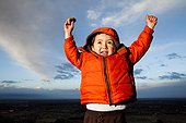 A young boy lifts hands in excitement outdoors in Fort Collins, Colorado.
