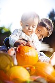 A little boy smiles and hugs his younger brother while seated on a pumpkin patch in Fort Collins, Colorado.