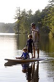 Six-year-old and four-year-old brothers ride with their father on a SUP
