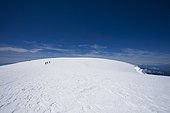 The summit of a large volcanic mountain with a sunny, blue sky above.